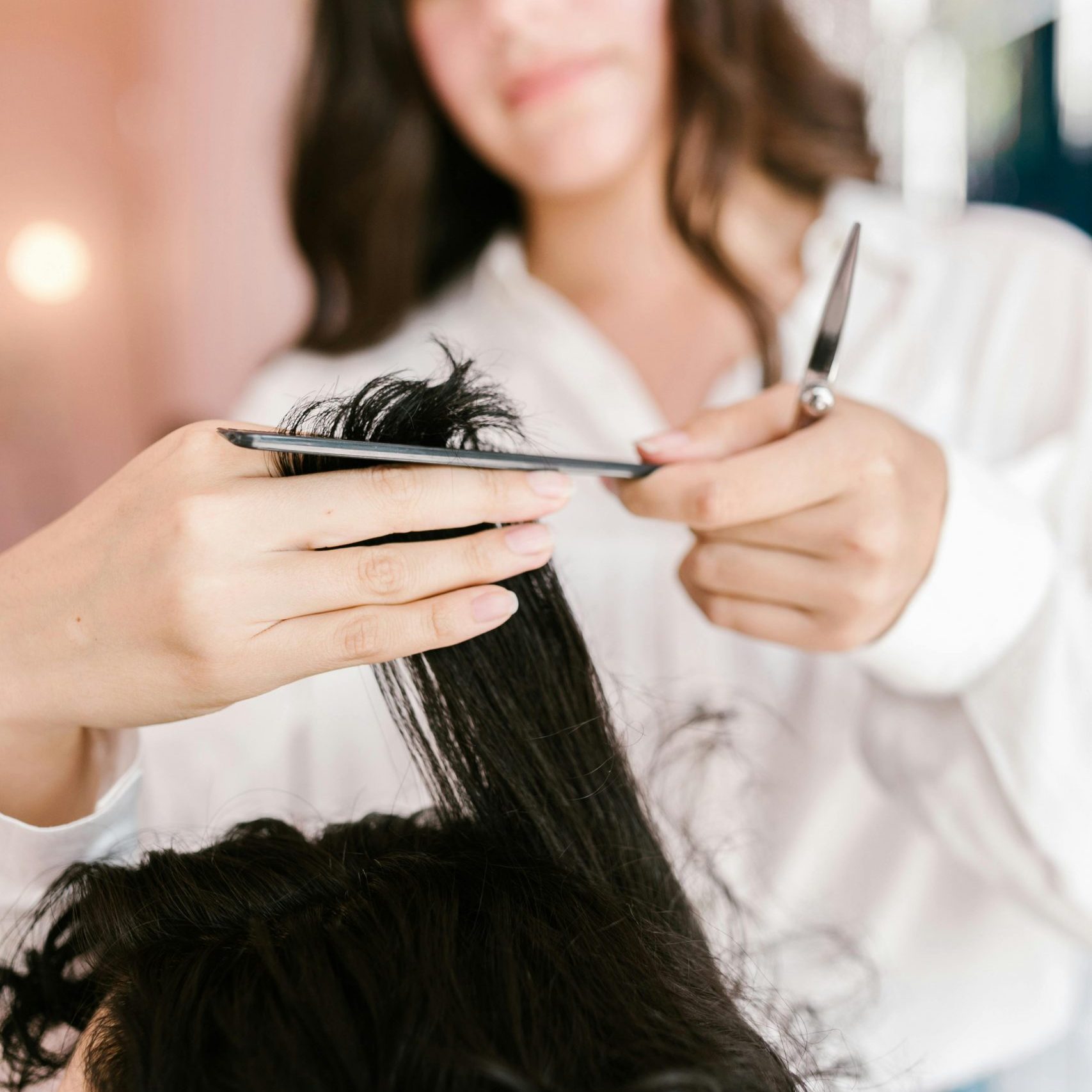 Close-up of hairstylist expertly cutting client’s hair in a salon setting.